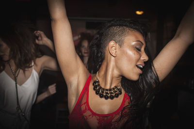 Portrait of happy young woman with arms raised
