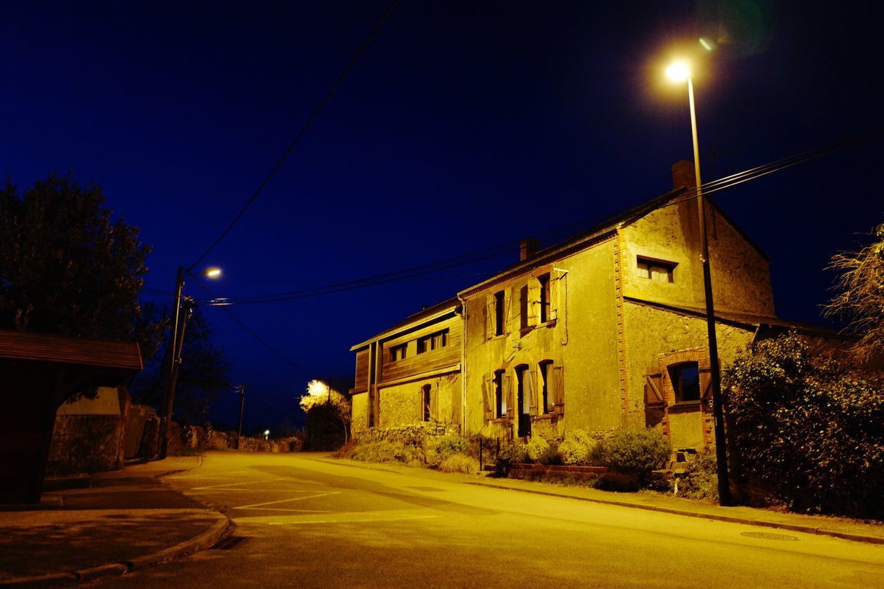 ILLUMINATED STREET BY BUILDING AT NIGHT