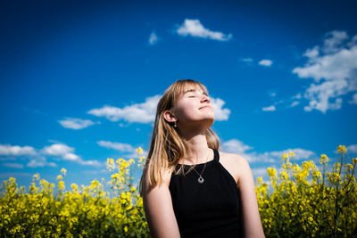 Low angle view of girl standing against blue sky