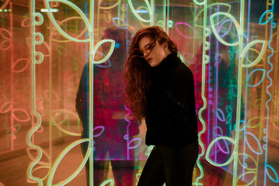 Full length of woman standing against illuminated wall at night