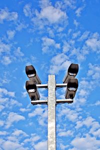 Low angle view of surveillance cameras against blue sky