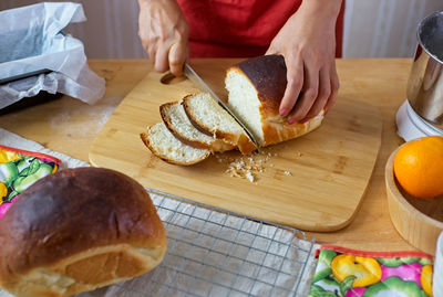 Close-up of woman cutting bread in kitchen