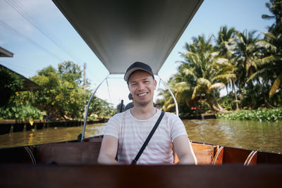 Portrait of smiling tourist on boat. man enjoys vacation time on boat trip to floating market.