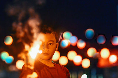 Boy holding lit sparklers in illuminated city at night