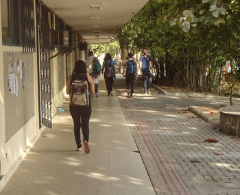 Rear view of people walking on footpath in city