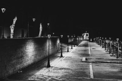 Empty footpath amidst illuminated buildings in city at night