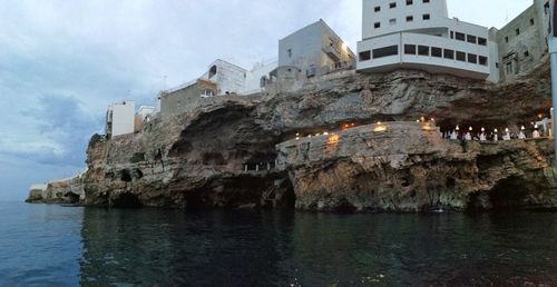 Buildings by sea against sky