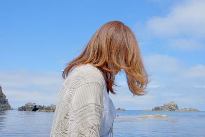 Woman looking at sea shore against sky