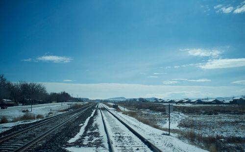 Railway tracks against blue sky during winter