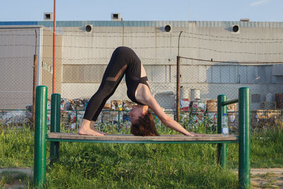 Woman exercising on built structure during sunny day