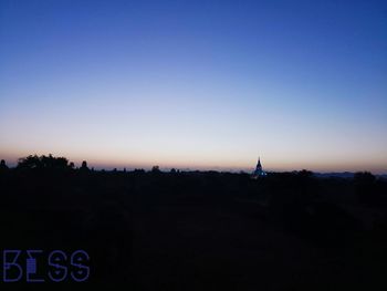 Silhouette trees and buildings against clear sky at sunset