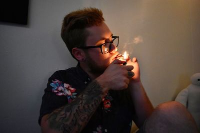 Close-up of young man smoking at home