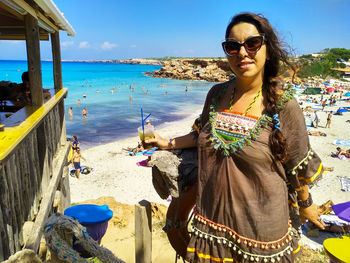 Young woman drinks a cool drink in the warm sea of cala saona in formentera in balearic islands