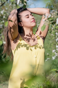 Portrait of young woman standing against plants