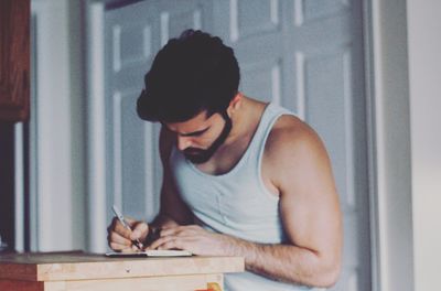 Close-up of man writing in book at table