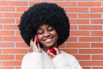 Portrait of young woman wearing sunglasses against brick wall
