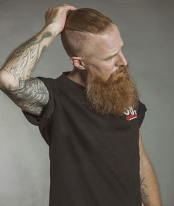 Man looking away while standing against gray background