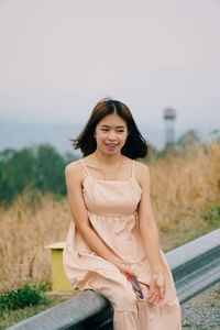 Portrait of smiling young woman standing against sky