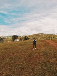 Woman photographing on field against sky