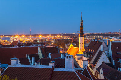 Illuminated cityscape against clear blue sky at night