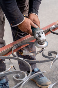 Man grinds metal with angle grinder in metal workshop. sparks fly on sides. male hand and instrument