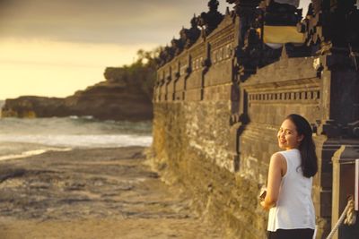 Woman standing at beach against sky