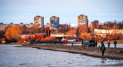 People standing by illuminated buildings against sky during autumn