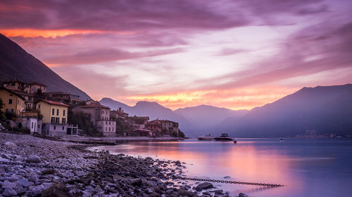 Scenic view of houses by mountains against sky during sunset