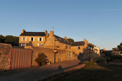 Buildings by street against clear blue sky