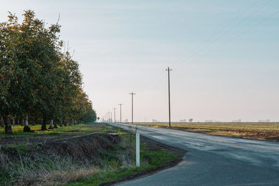 Empty road by field against sky