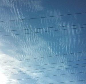 Low angle view of power lines against blue sky