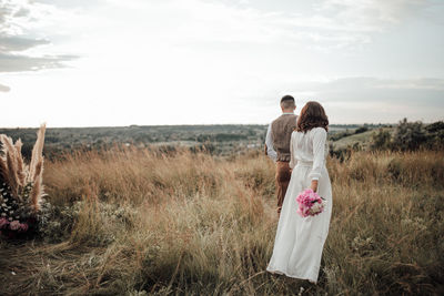 Rear view of couple on field against sky