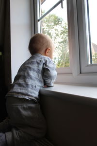Boy looking through window at home