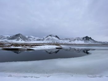 Frozen lake against snowcapped mountains against sky