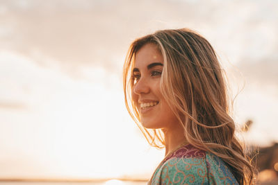 Portrait of young woman standing against sky