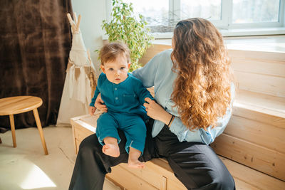 Mother with baby son on the background of a window and a wooden bench. high quality photo