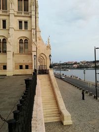 View of river by buildings against cloudy sky