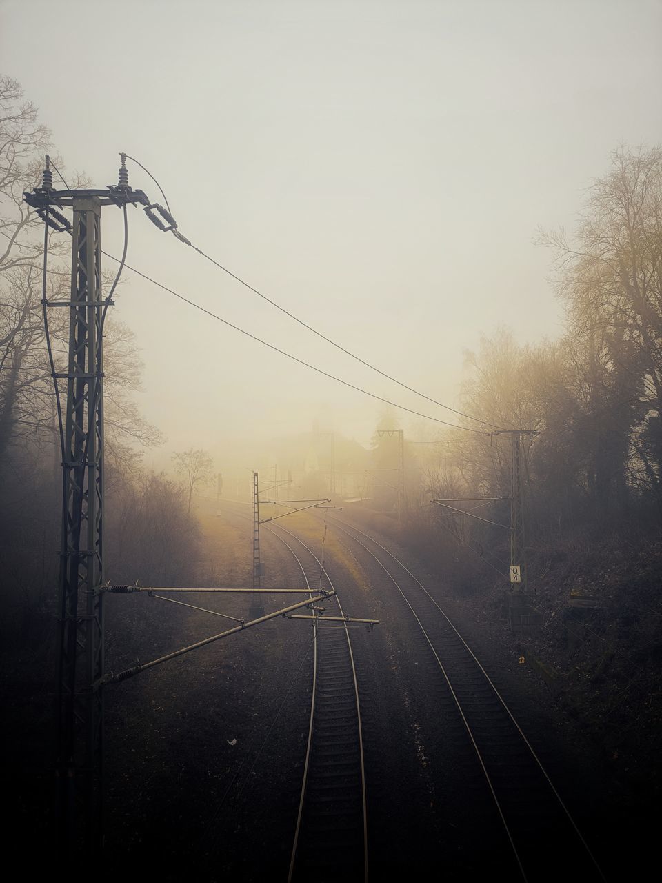 morning, cable, fog, railroad track, track, electricity, rail transportation, transportation, sky, nature, electricity pylon, darkness, power line, technology, line, no people, mist, power supply, tree, light, mode of transportation, dawn, sunlight, outdoors, plant, electrical supply, overhead power line, public transportation, silhouette