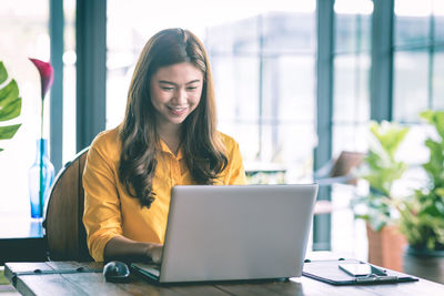 Portrait of smiling businesswoman using laptop in office