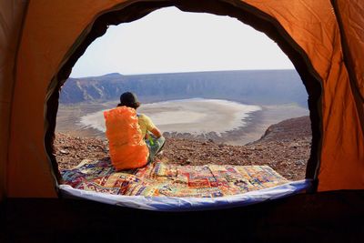 Rear view of woman seen through tent at volcanic landscape