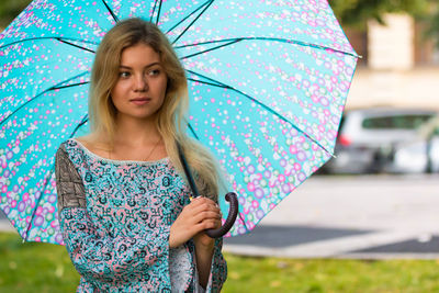 Thoughtful woman with umbrella looking away while standing at park