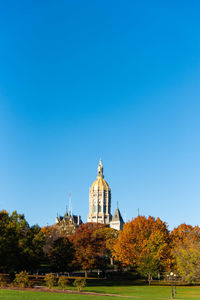 View of trees and buildings against blue sky