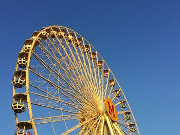 Low angle view of ferris wheel against blue sky