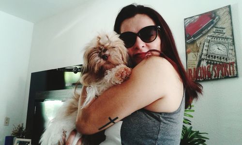 Young woman holding dog at home