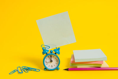 Low angle view of clock on table against yellow background