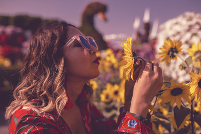 Close-up of young woman holding flower in ornamental garden at dusk