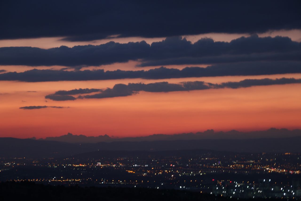 illuminated, mountain, cityscape, sky, city, night, scenics, sunset, mountain range, silhouette, building exterior, beauty in nature, built structure, cloud - sky, high angle view, architecture, dusk, landscape, nature, tranquil scene