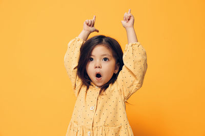 Surprised girl gesturing against yellow background