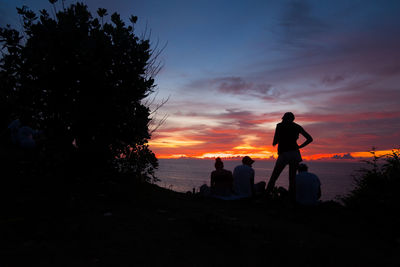 Silhouette people against orange sky during sunset