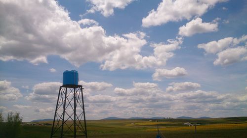 Water tower on field against sky